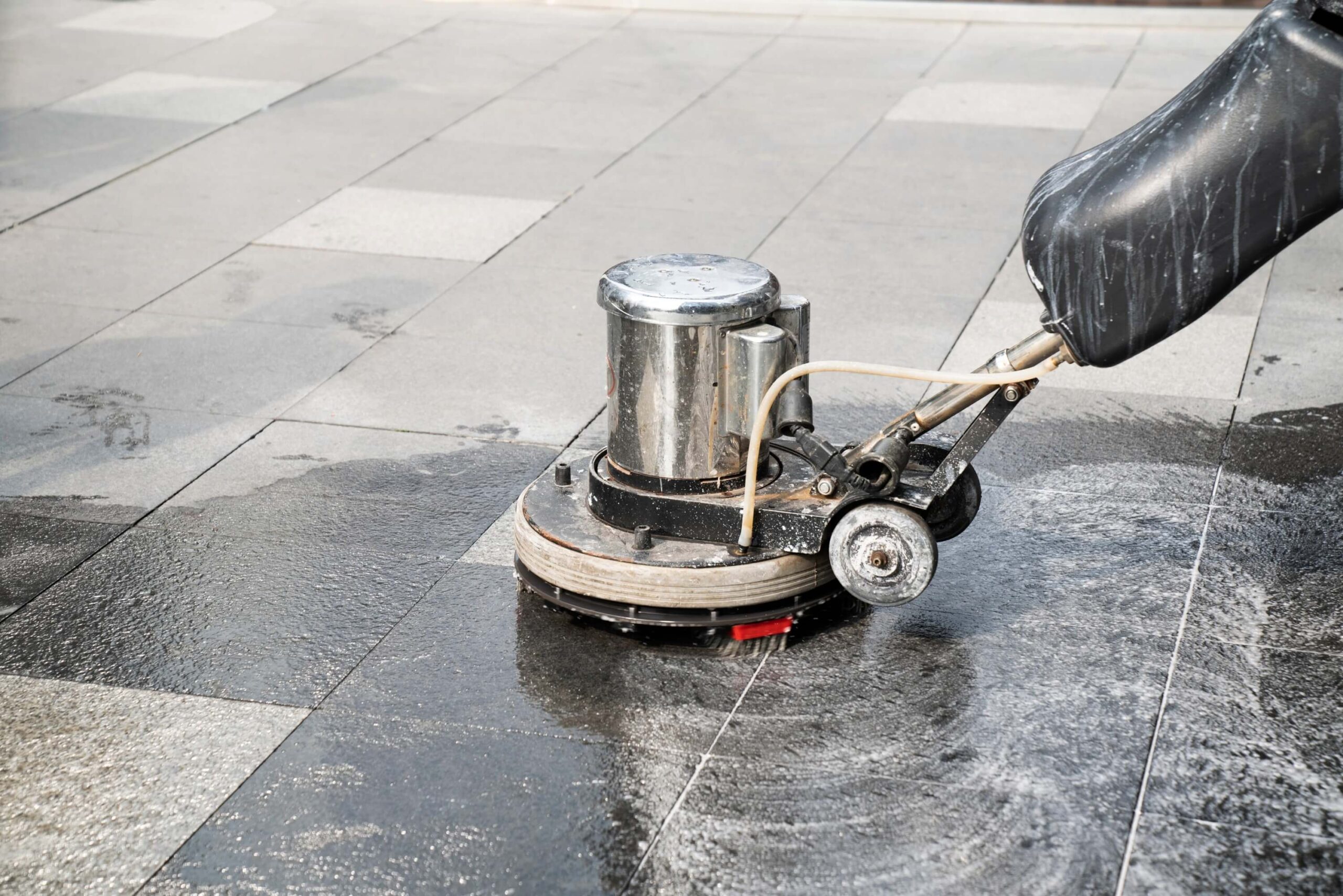 People cleaning outdoor walkway using a polishing machine